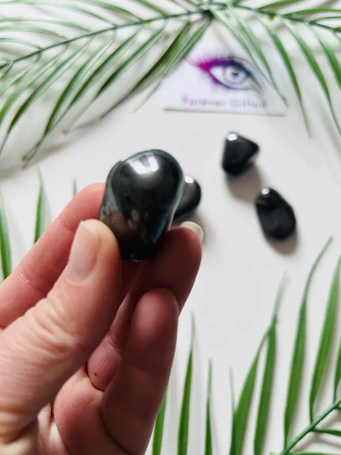 Hematite tumble stone, held in the hand