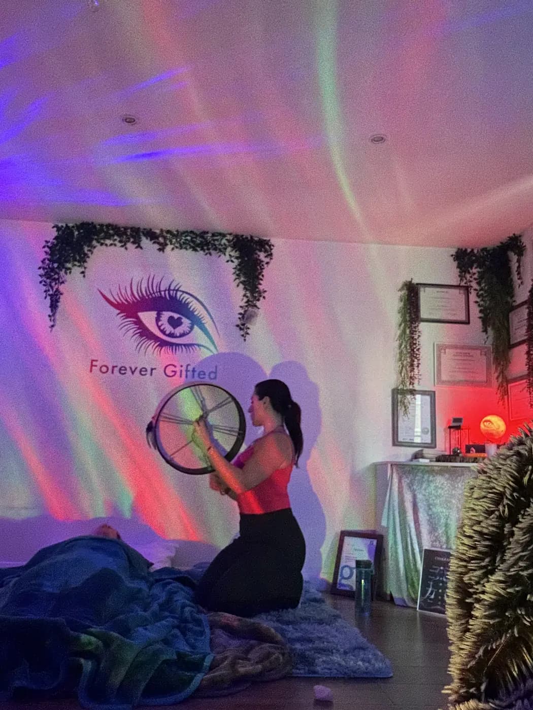 Filiz kneeling with a drum under aurora light in the cabin