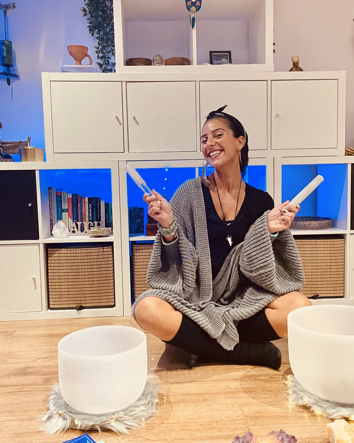 Filiz laughing, sitting cross-legged with two crystal singing bowls in her cabin