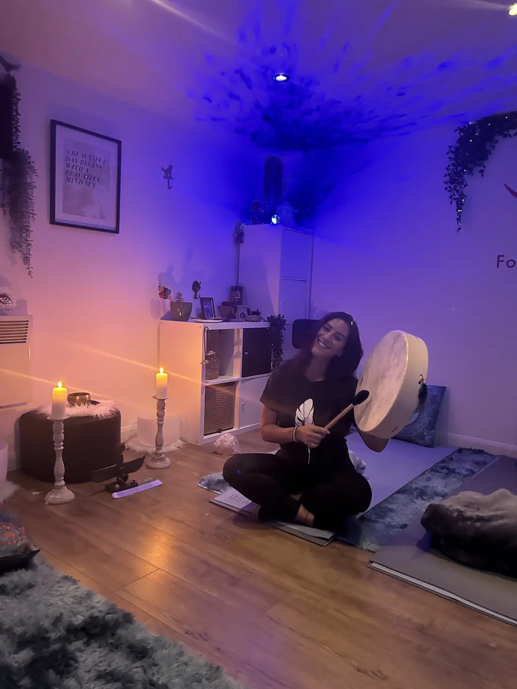 Filiz sitting on the cabin floor with her drum and candles lit