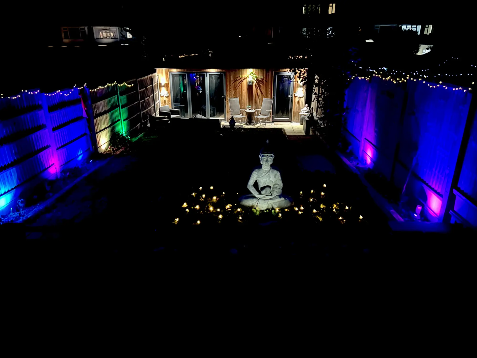 A garden at night lit by candles and coloured lights